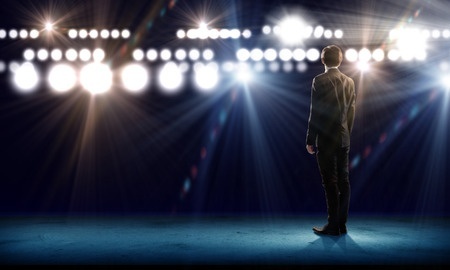 Stock photo of businessman giving a speech with stage lights.