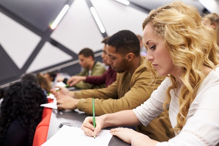 Photo of female taking notes in a university lecture.