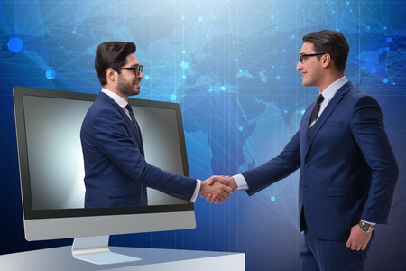 Image of videoconferencing equipment and two men shaking hands. 