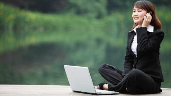 Stock photo of business woman talking on the phone with a laptop.