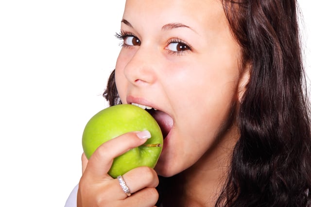 Stock image of young girl biting into an apple.