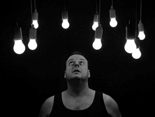 Stock photo image of man looking up at light bulbs in ceiling.