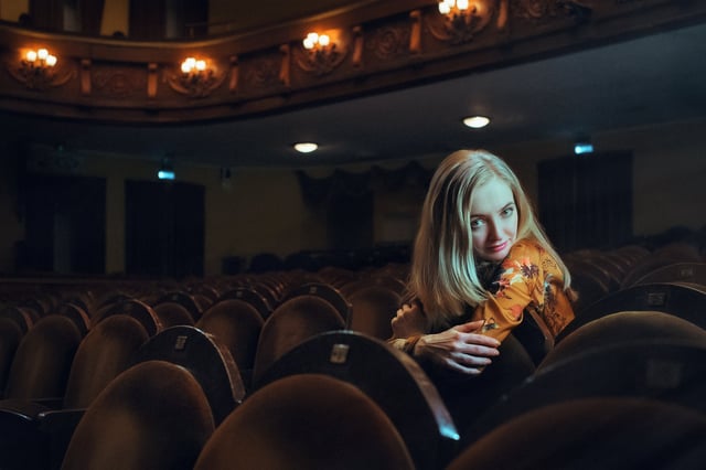 Stock photo of beautiful young woman sitting in audience.