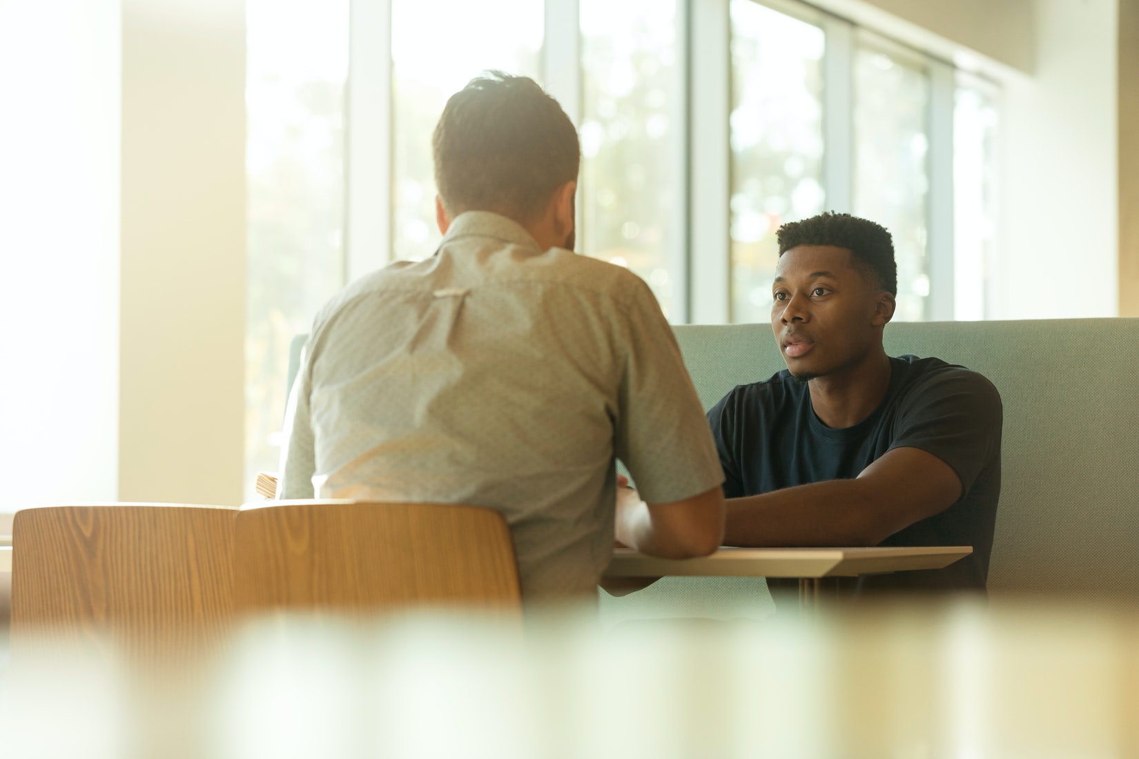 Stock image of Black man and White man having a conversation.