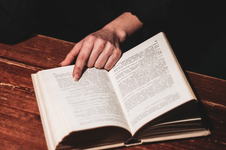 Stock photo of hand pointing to a page in a book.