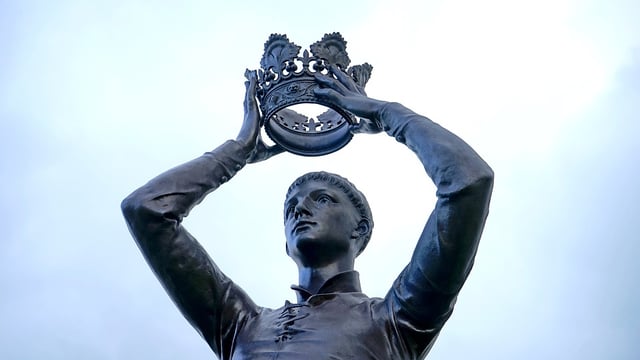 Statue of Shakespeare's Henry V placing crown on his head.