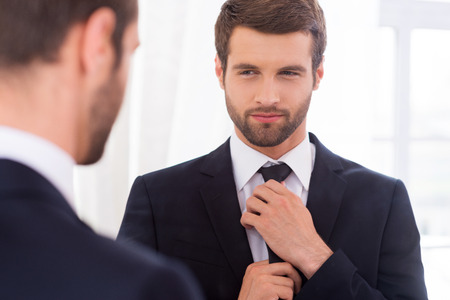 Stock photo of handsome young man with beard looking in the mirror.