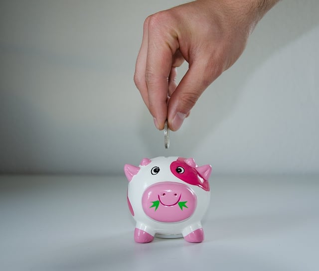 Stock image of man putting money in a piggy bank.